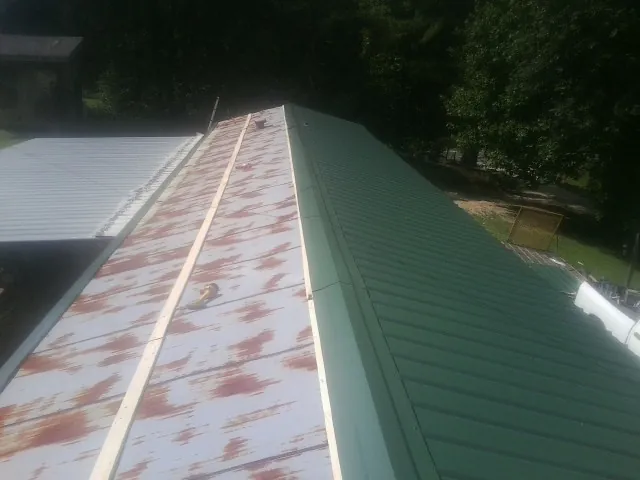 Old rusted panels beside newly installed green metal roofing — Wind Damage Roof Repair by Roofing Brothers in Cabot