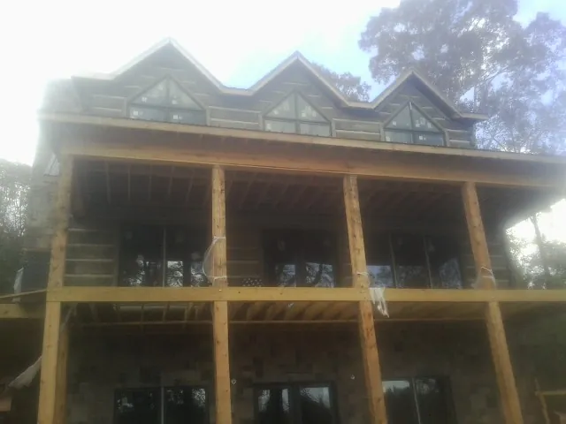 Dormers and porch framing on a large log home under construction — Roof Coating work by our crew in Cabot