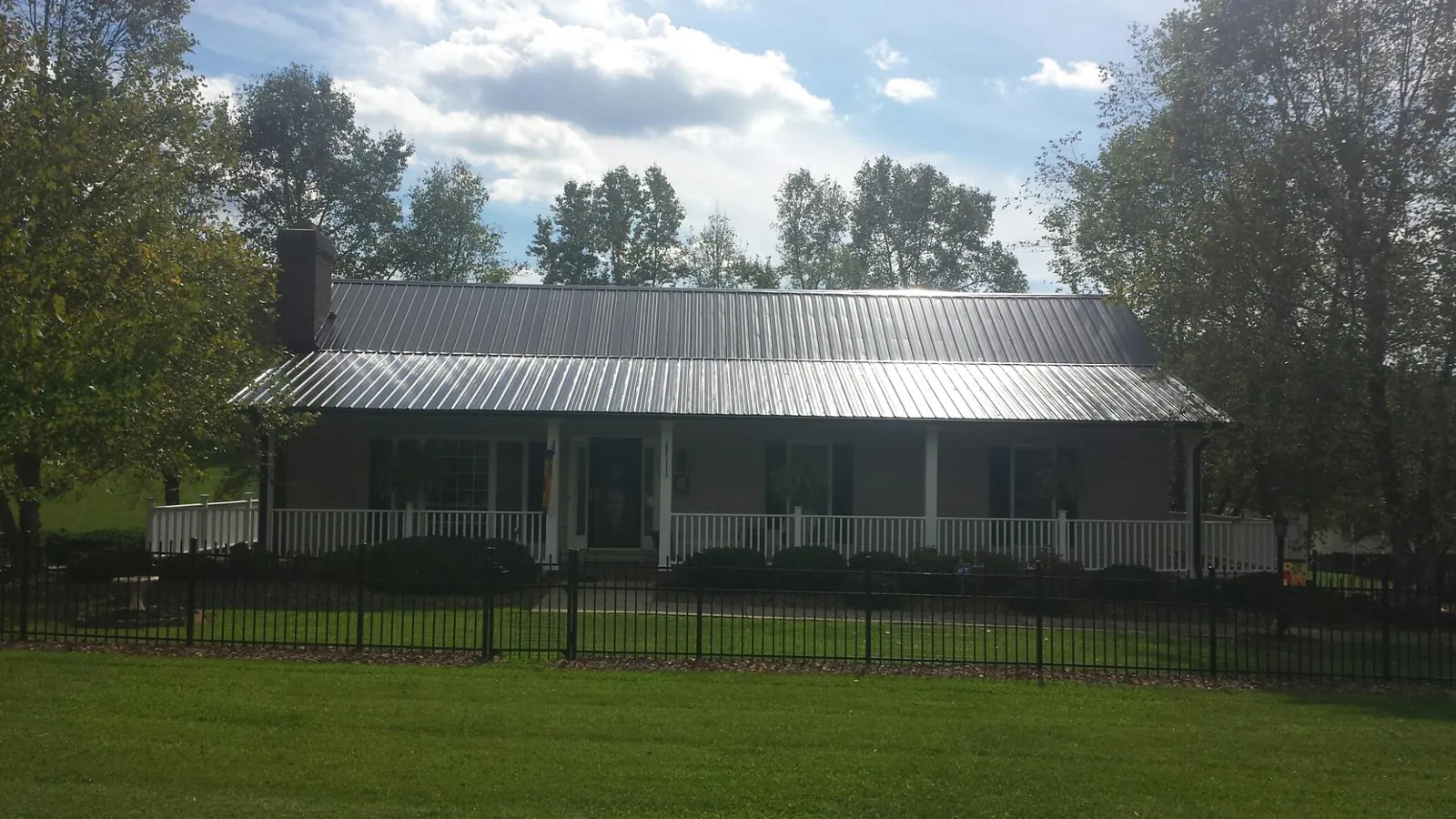 Gray metal roof on a brick ranch with a full width front porch — Gutter Guard Installation work by our crew in Cabot