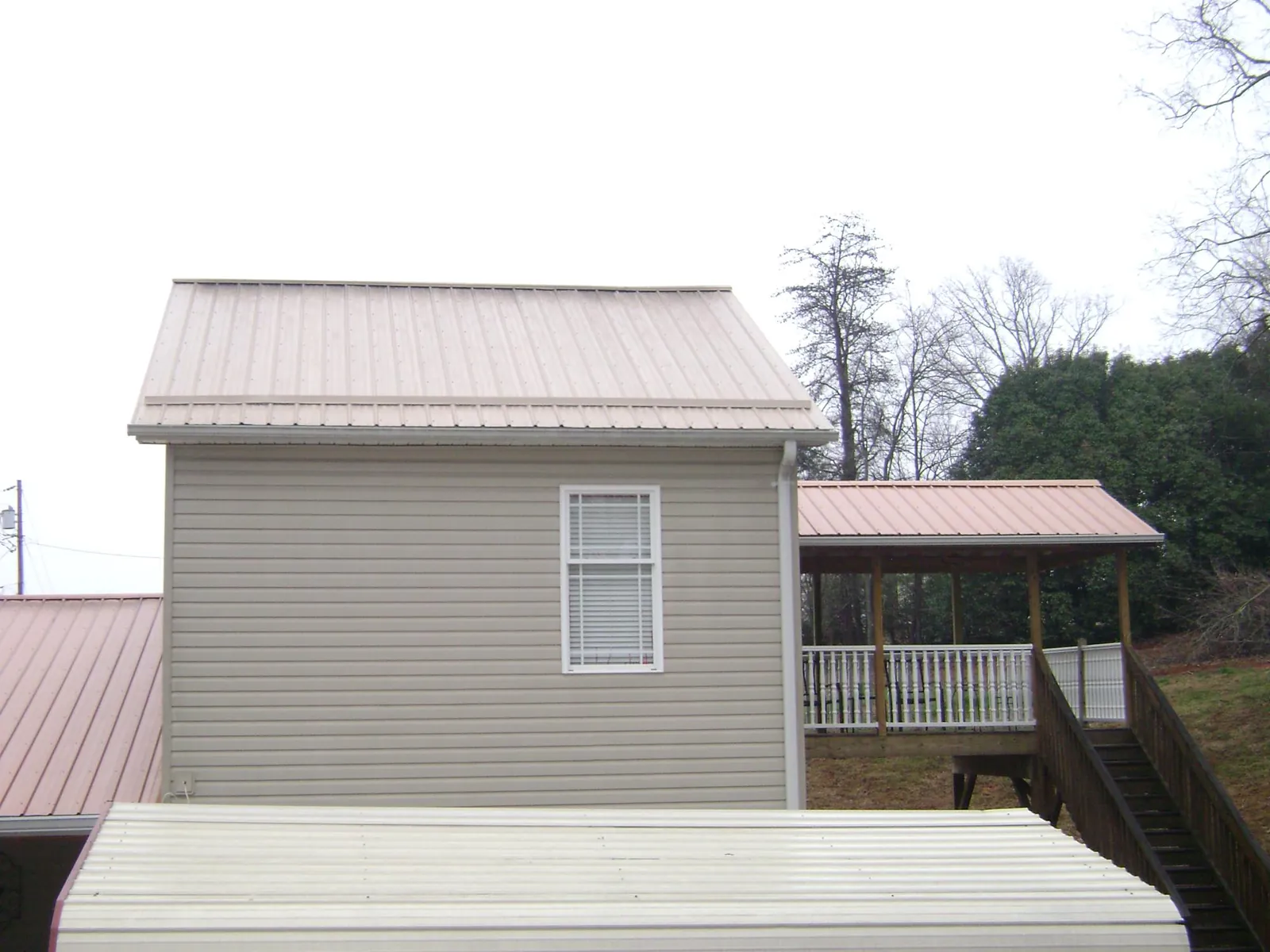 Tan metal roofs on a two story addition and attached porch, from a Roof Replacement job in Cabot
